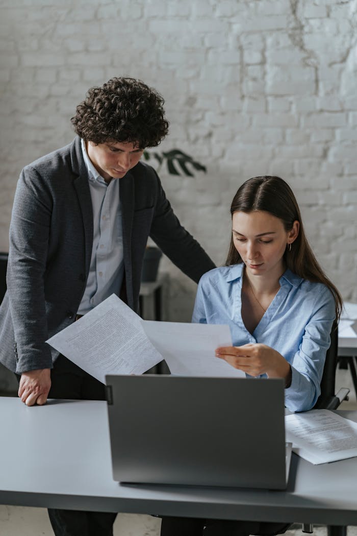 Two colleagues collaborate in a modern office, focusing on important documents.