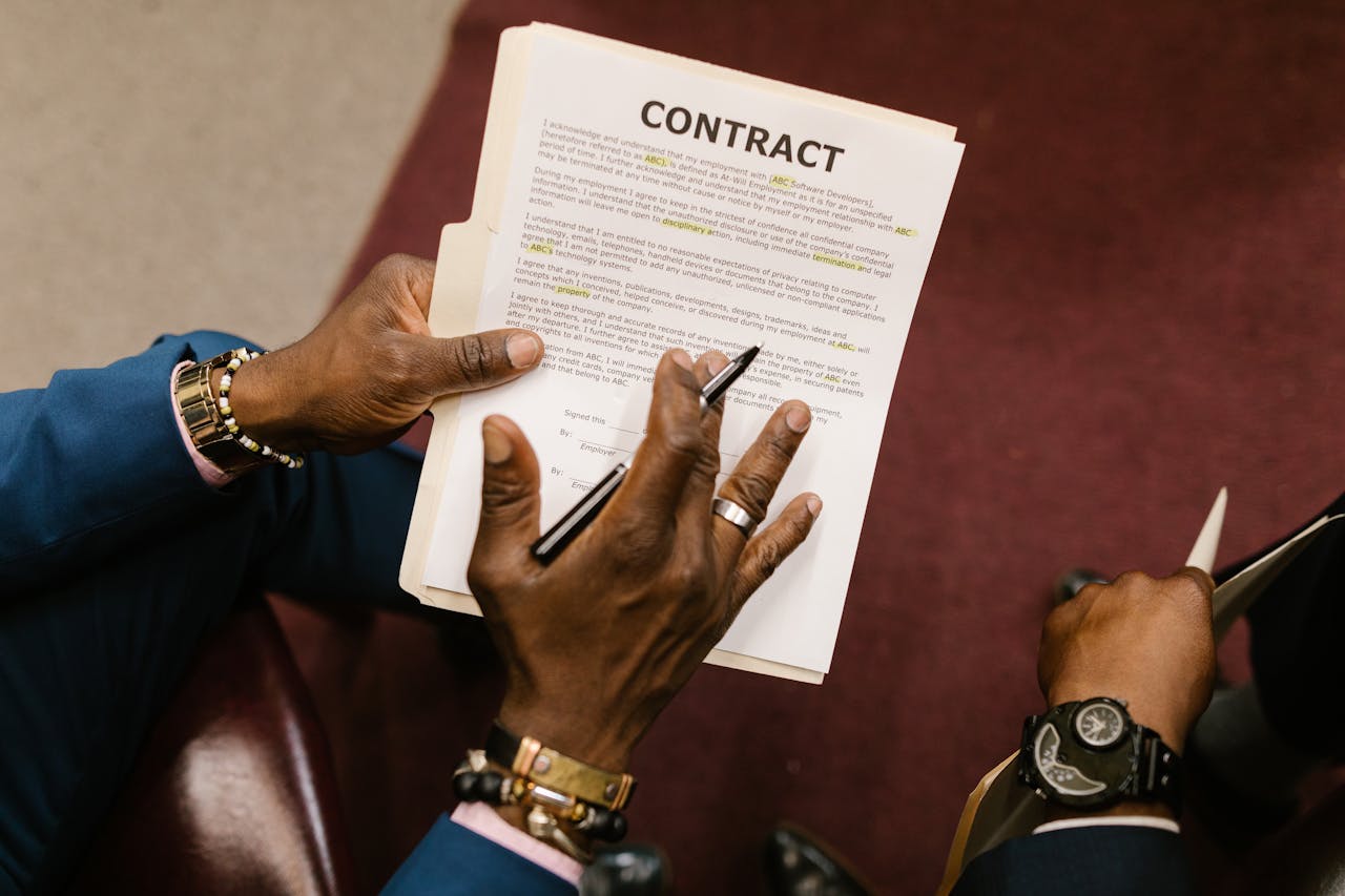 Two businessmen reviewing and signing a contract document in an office setting.